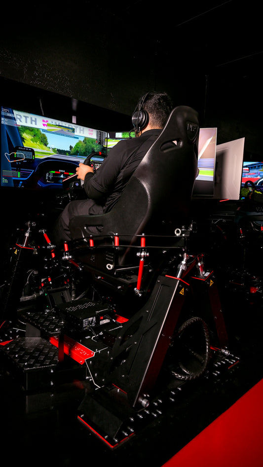 Man plays racing simulator with multiple screens