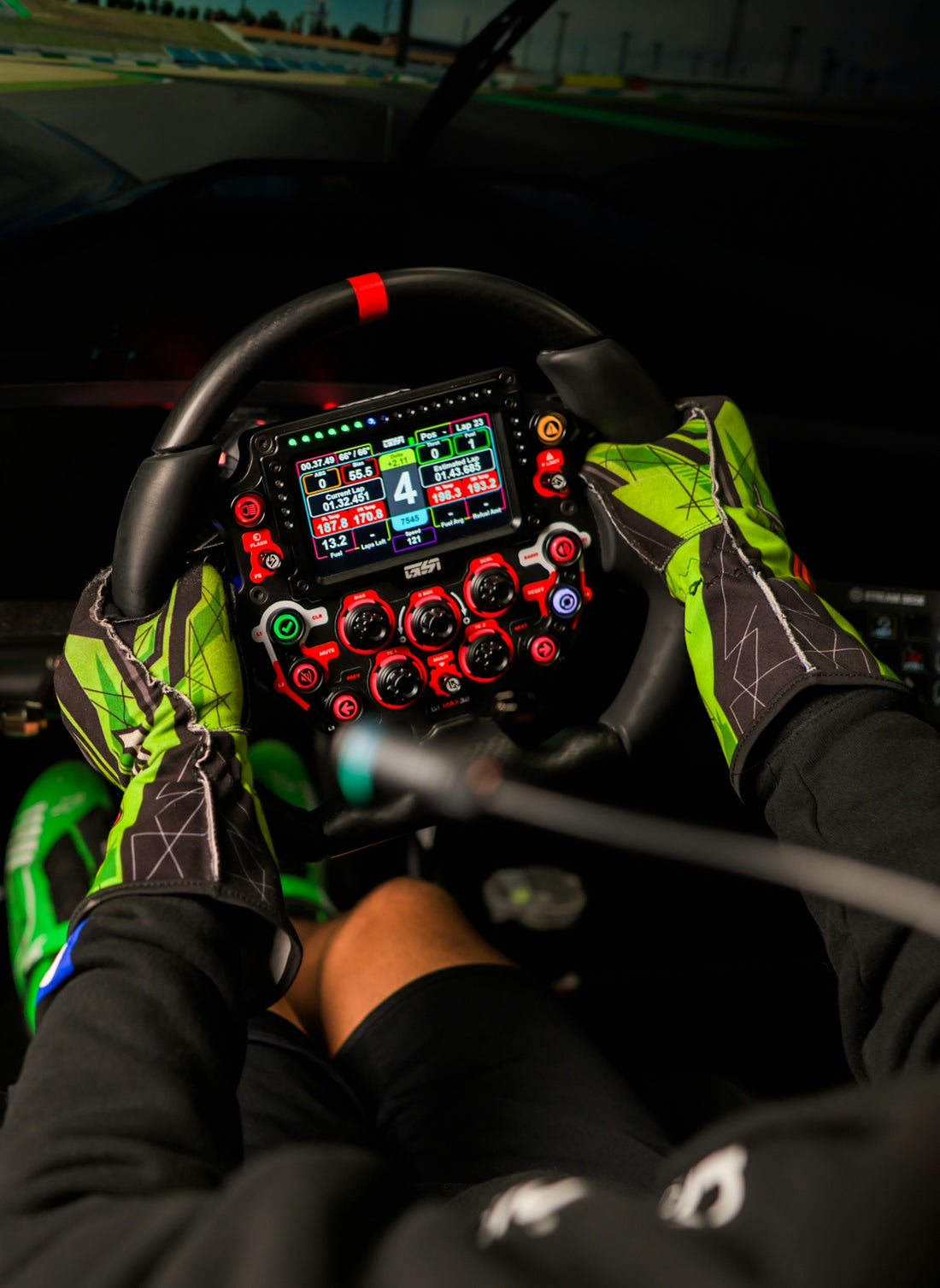 Hands in racing gloves grip a complex steering wheel